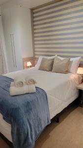 1 dormitorio con 1 cama blanca grande y toallas. en Apê em Itaipava, en Petrópolis