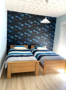 2 Betten in einem Schlafzimmer mit blauer Wand in der Unterkunft Maison au calme, 6 voyageurs in Riorges