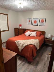ein Schlafzimmer mit einem Bett mit orangefarbener Bettwäsche und Kissen in der Unterkunft A great house by Fonner Park in Grand Island
