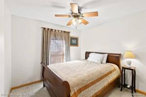 a bedroom with a bed and a ceiling fan at Newer Cottage on the Lake, ample space for boats in Harsens Island
