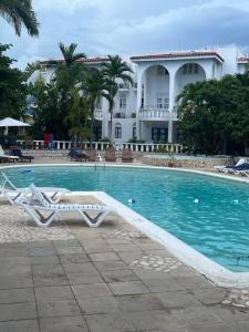 a swimming pool with two lounge chairs in front of a house at Beachfront Luxe Apt in Runaway Bay