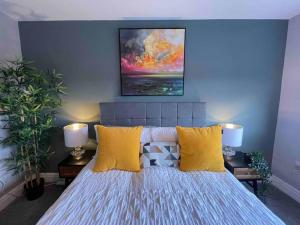 una camera da letto con un letto con cuscini gialli e un dipinto di Luxury 1 bed Flat + sofa bed- Dudley 
