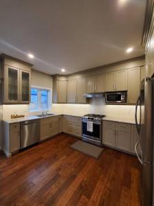 a large kitchen with wooden floors and stainless steel appliances at 4 BD Family Retreat in Stratford