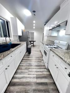 una cocina blanca con armarios blancos y fregadero en Little Bettys Cottage en Torrance