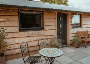 a patio with a table and chairs in front of a cabin at Rose Hideaway - Forest of Dean Cosy Cabin Retreat in Yorkley