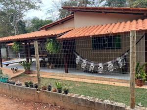 una casa con un perro en una jaula en Serra do cipó Casa do Fábio en Santana do Riacho