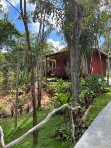 a red house in the middle of a yard with trees at Refúgio Integração in Mata de Sao Joao