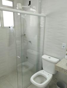 a bathroom with a toilet and a glass shower at Duplex Encantador in Guarapari