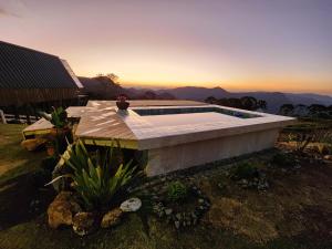 a swimming pool on top of a house with the sunset at Cabana Alpes in São Bento do Sapucaí