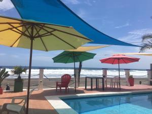 Barra de Santiago的住宿－MARDEORO BEACH HOUSE，海滩旁的游泳池配有遮阳伞和椅子