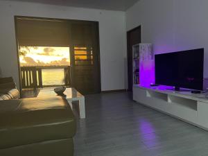 ein Wohnzimmer mit einem Sofa und einem Flachbild-TV in der Unterkunft Villa Toa Pearl Bora Bora in Bora Bora