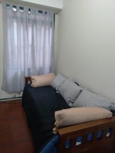 una cama con almohadas frente a una ventana en Departamento céntrico en Mendoza