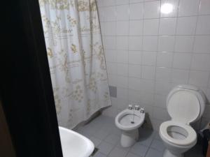 y baño con aseo, lavamanos y cortina de ducha. en Departamento céntrico en Mendoza