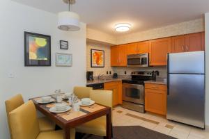 a kitchen with a table and a stainless steel refrigerator at Residence Inn by Marriott Arlington South in Arlington