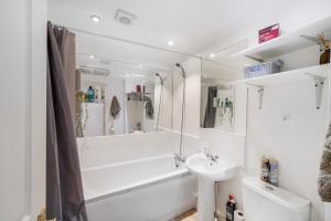 Baño blanco con bañera y lavamanos en LiveStay - Apartments in Bayswater London, en Londres