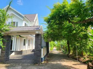 une maison blanche avec un arbre à côté d'une rue dans l'établissement Tranquil Retreat Lux Villa in HungYen Countryside, à HÆ°ng YÃªn