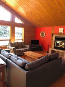 a living room with a leather couch and a fireplace at Chalet L'Érable Mont-Tremblant/Lac Supérieur & SPA in Lac-Superieur