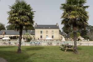 two palm trees and a picnic table in front of a building at Mobilhome tout équipé in Quimper