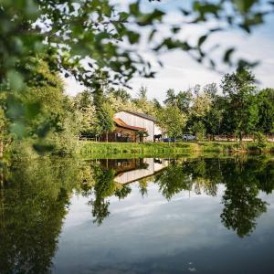 a barn is reflected in the water of a lake at Apartment Country House Zaton in Tišina