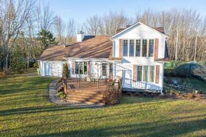 a house with a large deck in the yard at Chalet BIA - Cap au Sud in Trois-Lacs