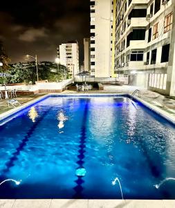 a large blue swimming pool in a city at night at Casa de la Playa in Macuto