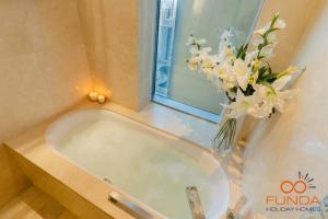 een badkamer met een bad en een vaas met bloemen bij Luxe high floor Studio in address 36 in Dubai
