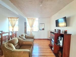 uma sala de estar com um sofá e uma televisão em Alojamiento Comodo con Vista Espectacular em Riobamba