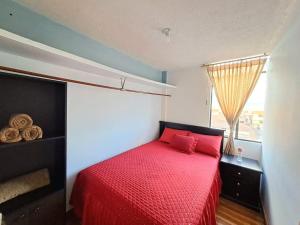 um quarto com uma cama vermelha e uma janela em Alojamiento Comodo con Vista Espectacular em Riobamba