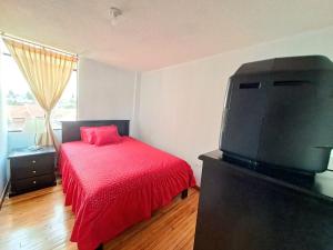um quarto com uma cama e uma televisão de ecrã plano em Alojamiento Comodo con Vista Espectacular em Riobamba