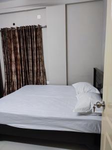 una camera da letto con un letto con lenzuola bianche e una finestra di Rahul's Castle Guest House a Visakhapatnam