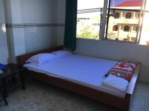 a small bed in a room with a window at Khách sạn Thiên Phúc in Cà Mau