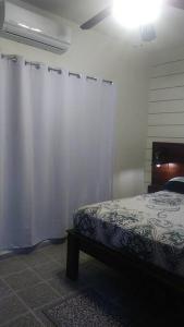 a bedroom with a bed and a white curtain at Cozy Townhouse & Terrace/Pool in La Ceiba