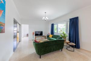 a living room with a green couch and a tv at Familiewoning met privé zwembad in Willemstad