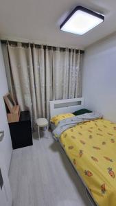 1 dormitorio con 1 cama con manta amarilla en Pavilla city 401 two bedroom house en Busan