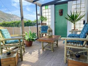 a patio with chairs and a wooden table and a table at Crescent Corner Vacation Home in Cape Town