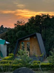 a small wooden cabin with a sunset in the background at Dhauladhar View Village Resort in Dharmsāla