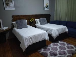 um quarto com 2 camas e um sofá azul em Inkanyezi guest house em Durban