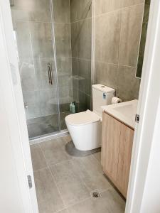 a bathroom with a shower and a toilet and a sink at Sunny Beachside Home in Orewa
