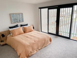 a bedroom with a large bed and a large window at Sunny Beachside Home in Orewa