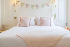 Una cama blanca con almohadas y una pancarta encima. en Dreamy Town House Apartment in Dunkeld en Birnam