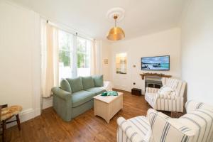 a living room with a green couch and chairs at Dreamy Town House Apartment in Dunkeld in Birnam