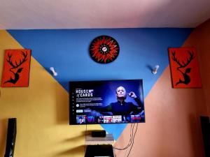 a flat screen tv hanging on a wall with a clock at Lux Suites Solar Holiday Apartments in Shanzu