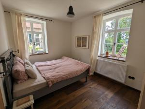 a bedroom with a bed and two windows at Alter Kornspeicher im Münsterland in Greven