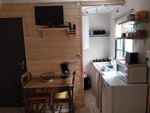 a small kitchen with a table and a tv on a wall at Petit studio dans la prairie in Saint-Auban