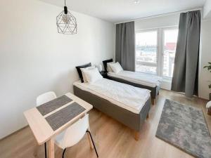 a bedroom with two beds and a table and a window at StyleStudio Areena1 in Tampere