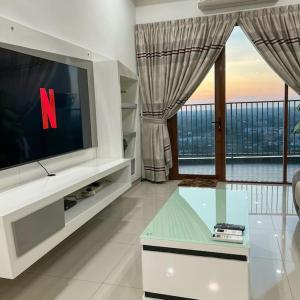 a living room with a tv and a large window at Taiping Homestay near Lake Garden with Sunset View in Taiping