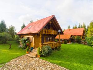 Cabaña de madera con techo rojo en un patio verde en Chatka Ustrzyki, en Ustrzyki Dolne