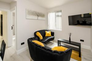 a living room with a black couch and yellow pillows at CommonSide Luxury in Mitcham
