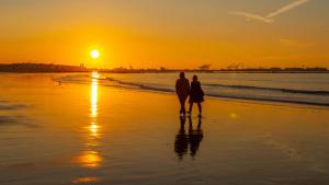 dwoje osób stojących na plaży o zachodzie słońca w obiekcie Luxury Seaside Cottage 28 w mieście Knokke-Heist