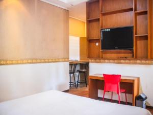 Hotel Sukamulya Pasteur في باندونغ: غرفة بسرير ومكتب وكرسي احمر